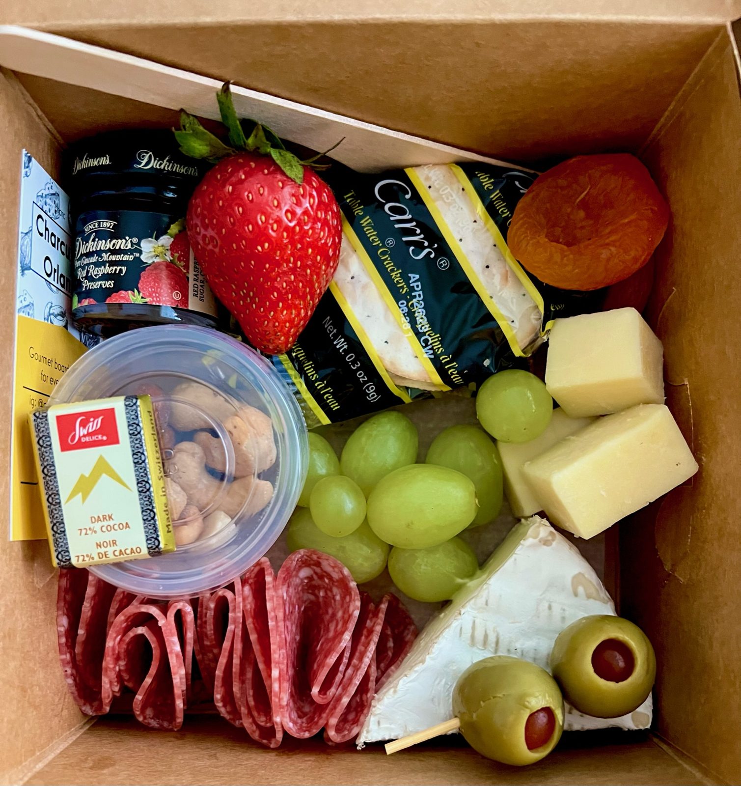 Charcuterie delivery box with salami, cheese, grapes, and preserves