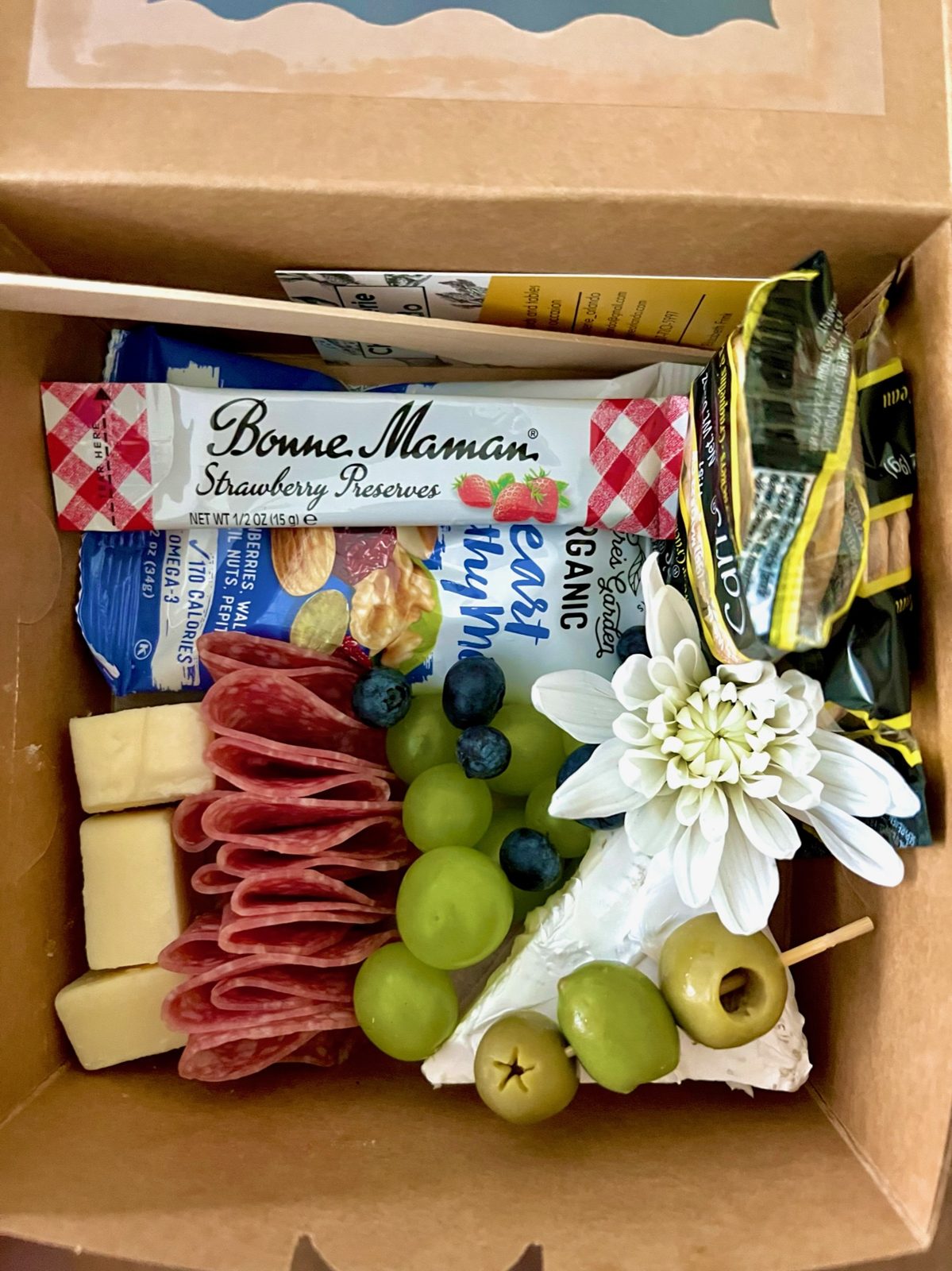 Boxed charcuterie delivery with meat roses, olives, and jam