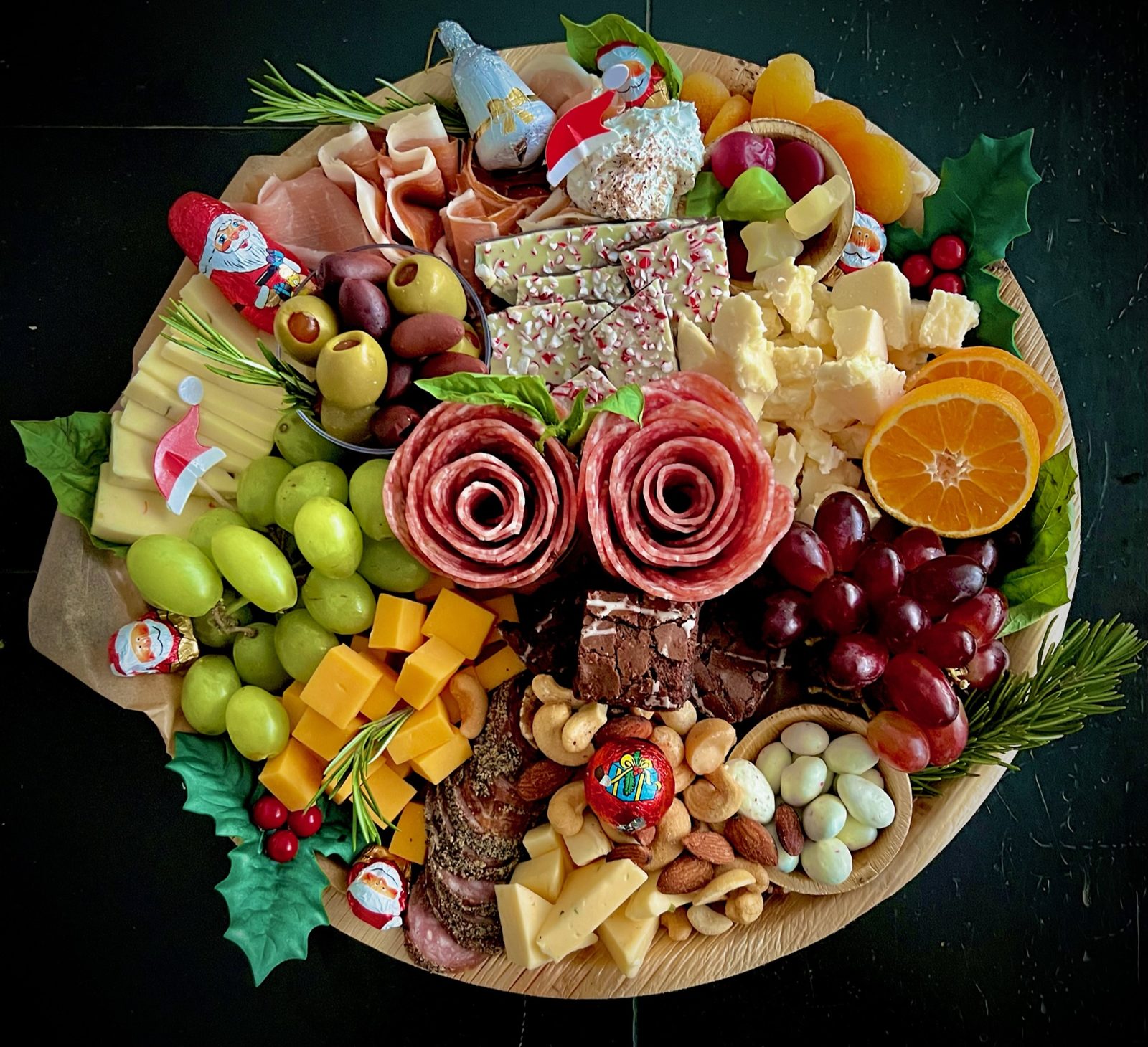 Holiday charcuterie board with cranberries, holly, and cheeses