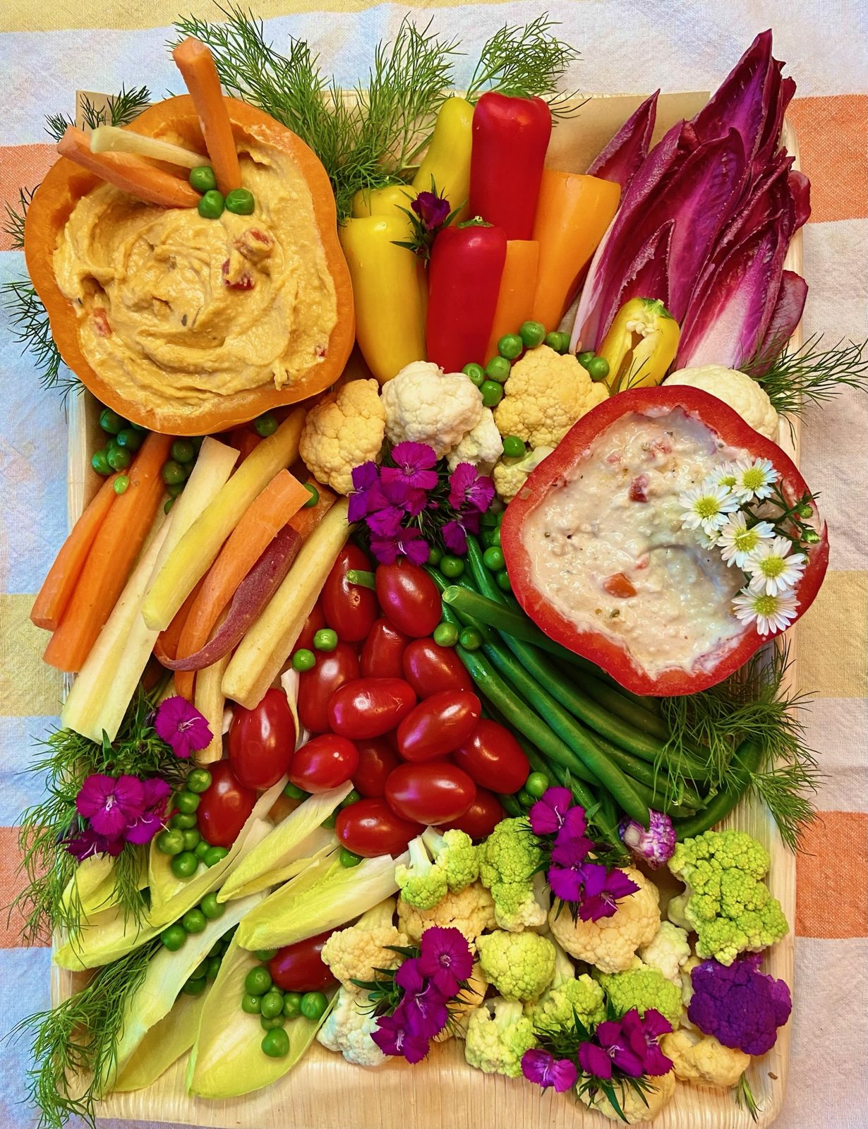 Plant-based board with roasted peppers, dips, and vegetables