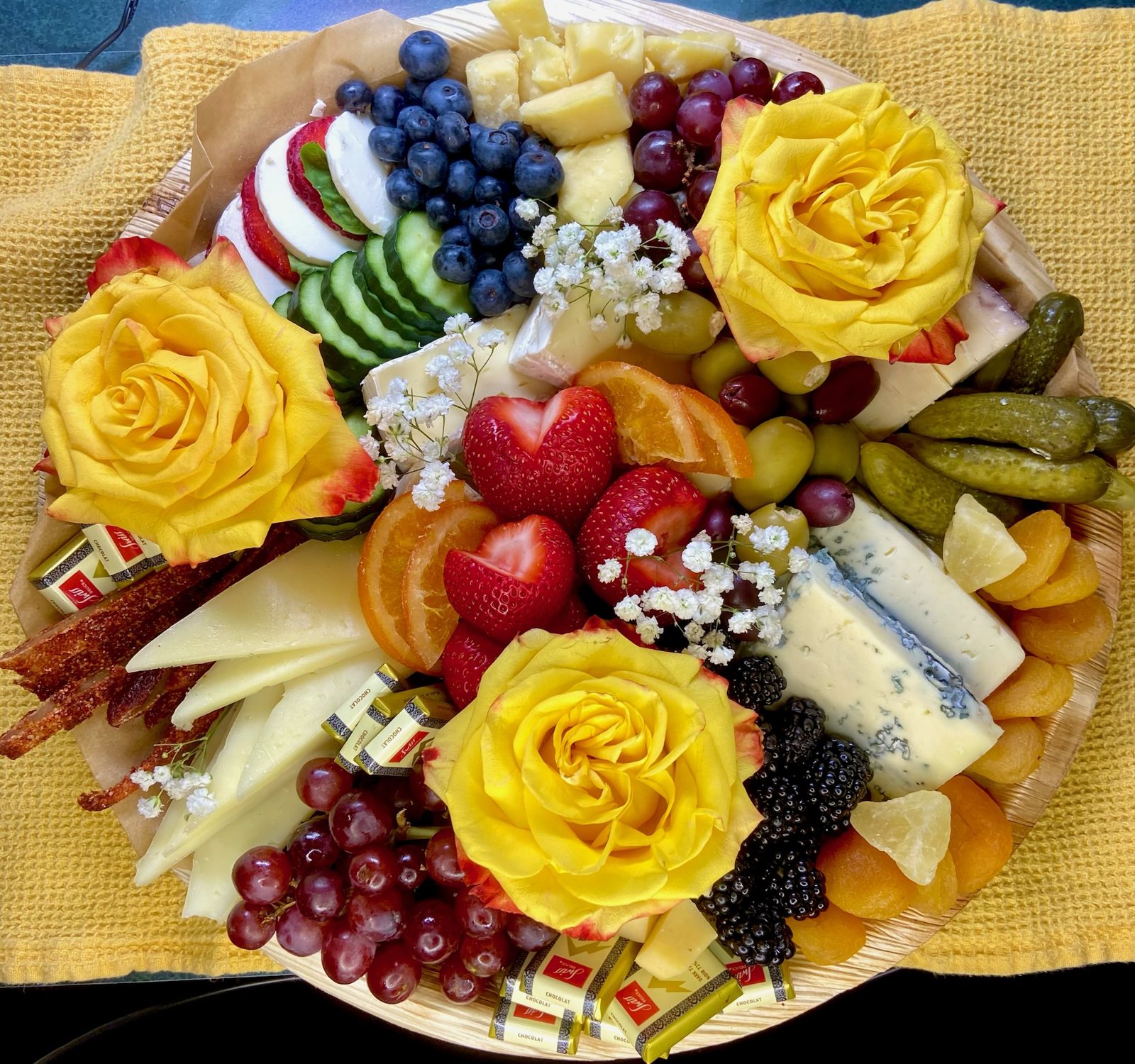 Round board with blue cheese, strawberries, and yellow florals