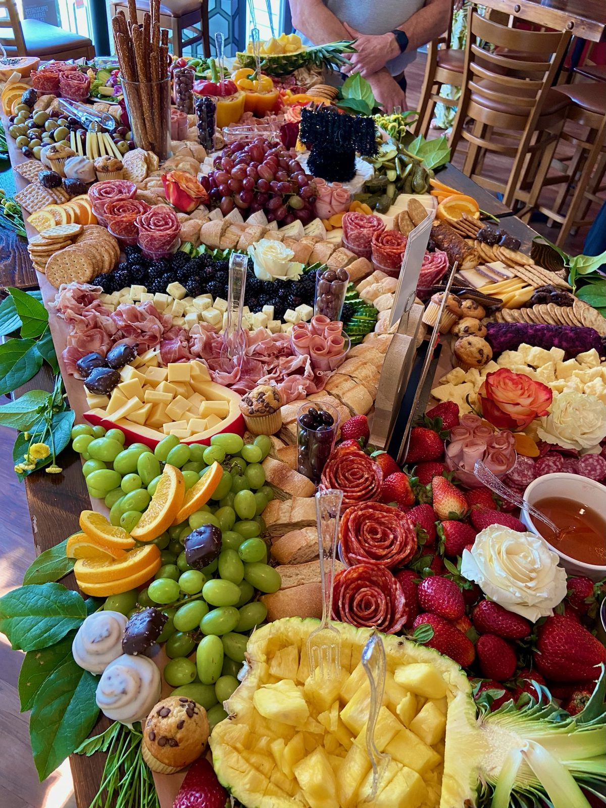 Rectangular charcuterie board with pineapple, grapes, and meat roses