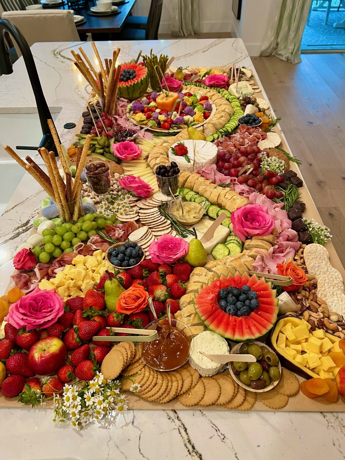 Wedding cocktail-hour grazing table styled with florals and fresh fruit